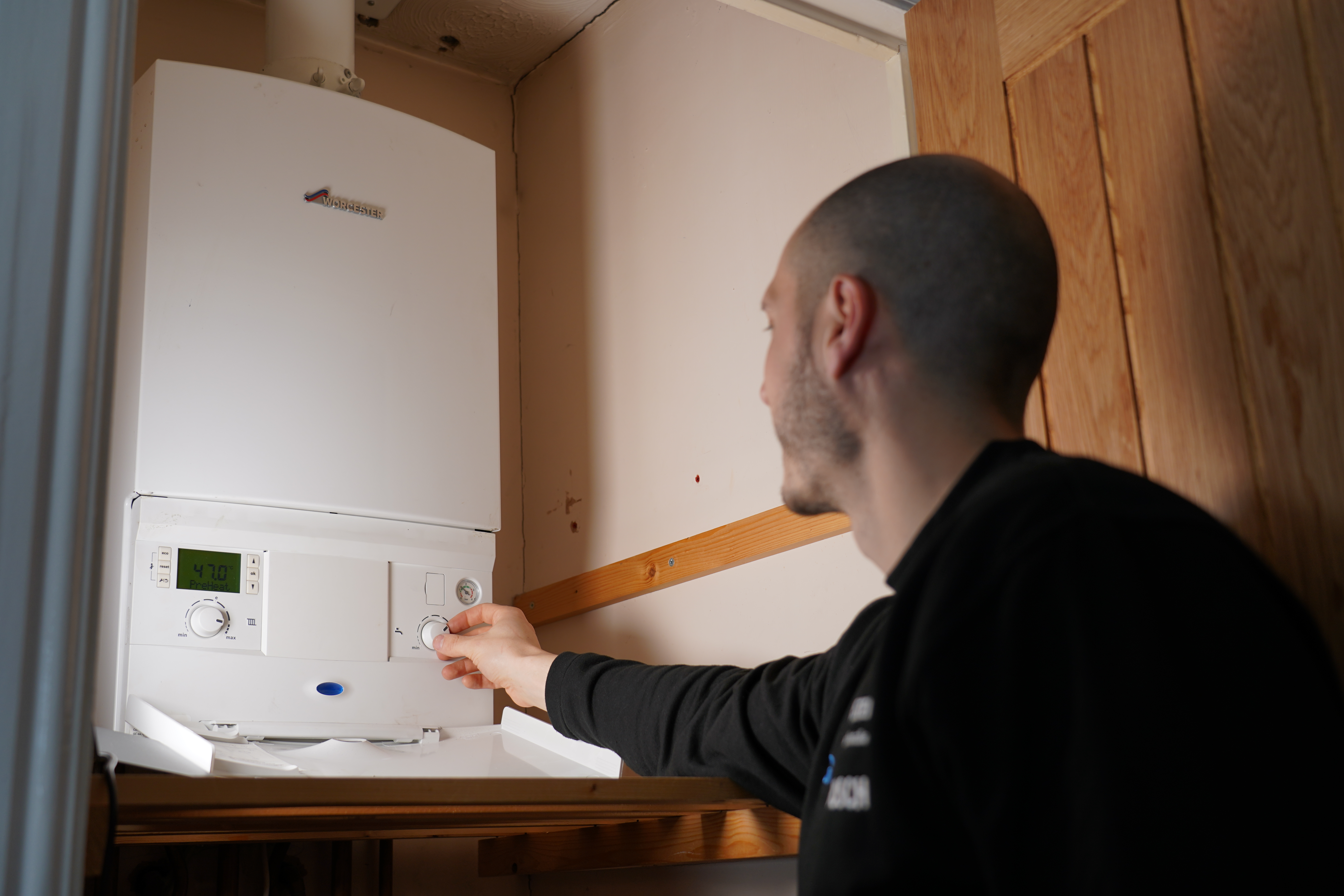 Photo of engineer adjusting a dial on a boiler